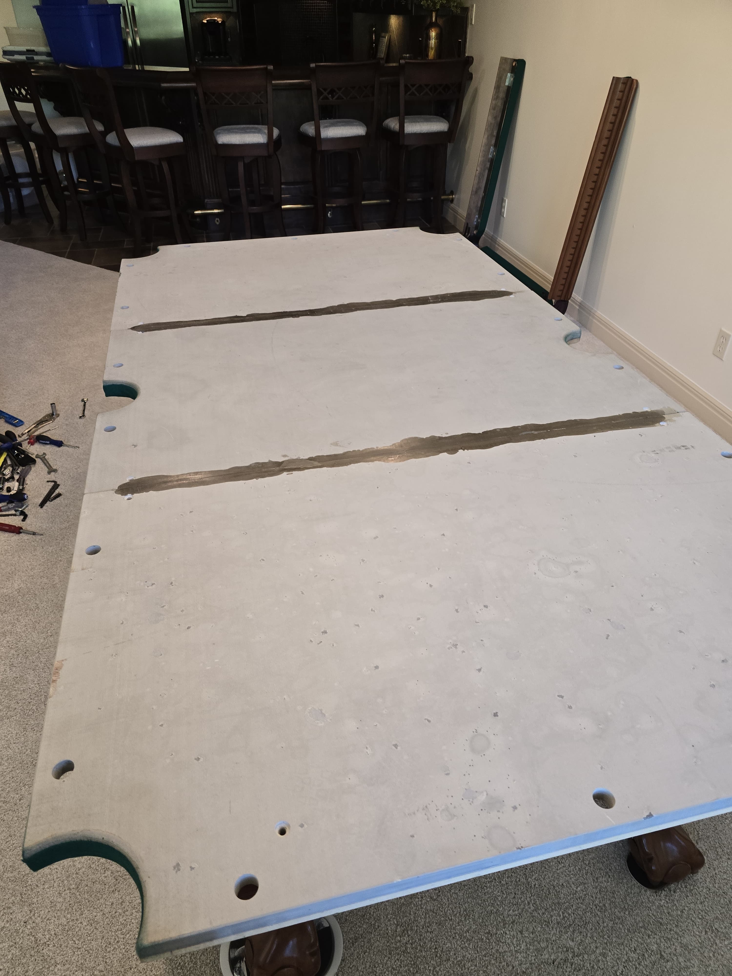 A pool table with the felt off: three-piece slate on the frame, seams filled