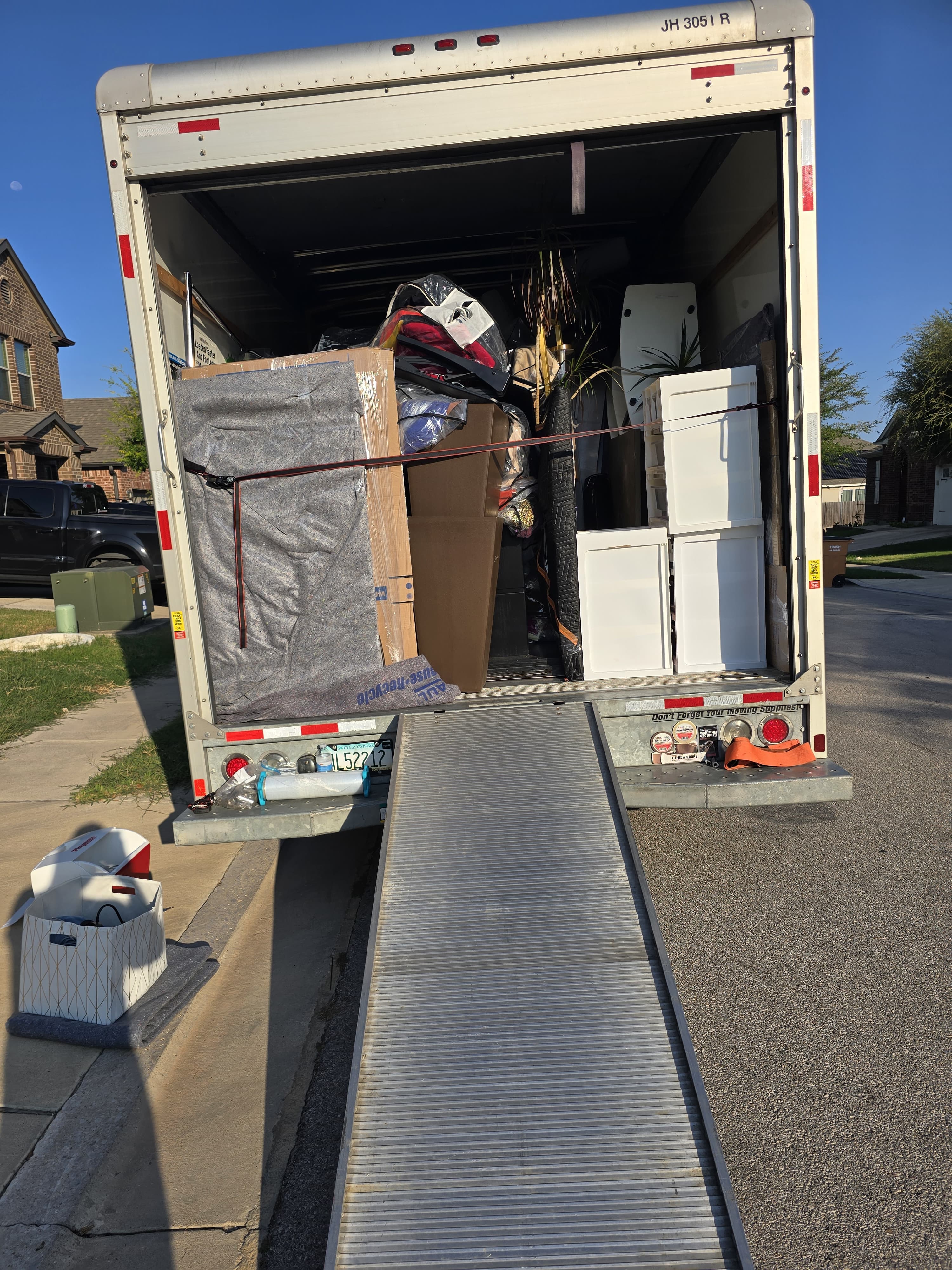 A loaded box truck with the ramp down, furniture padded and strapped