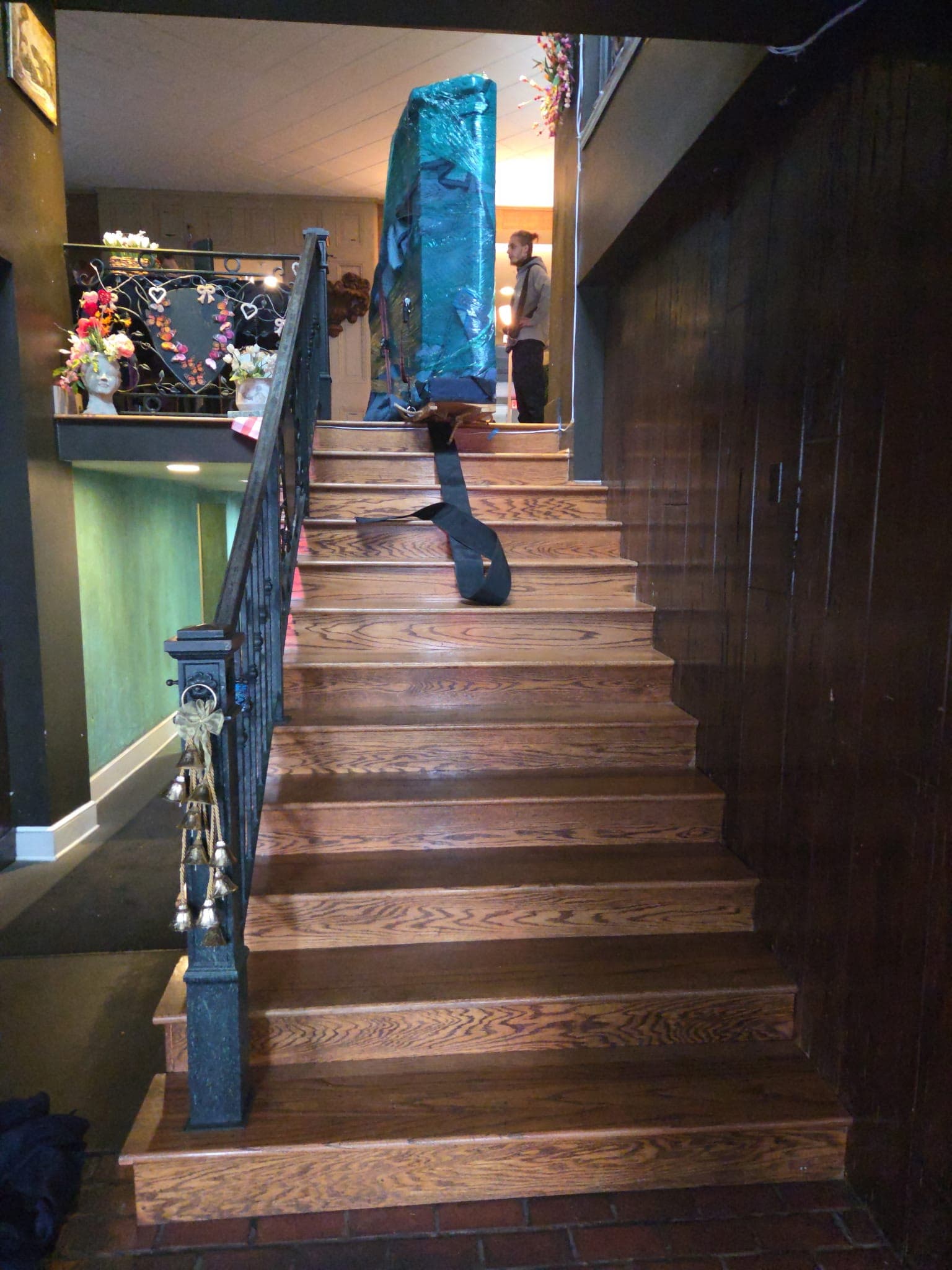A pad-wrapped upright at the top of a wooden stair, strapped for the descent