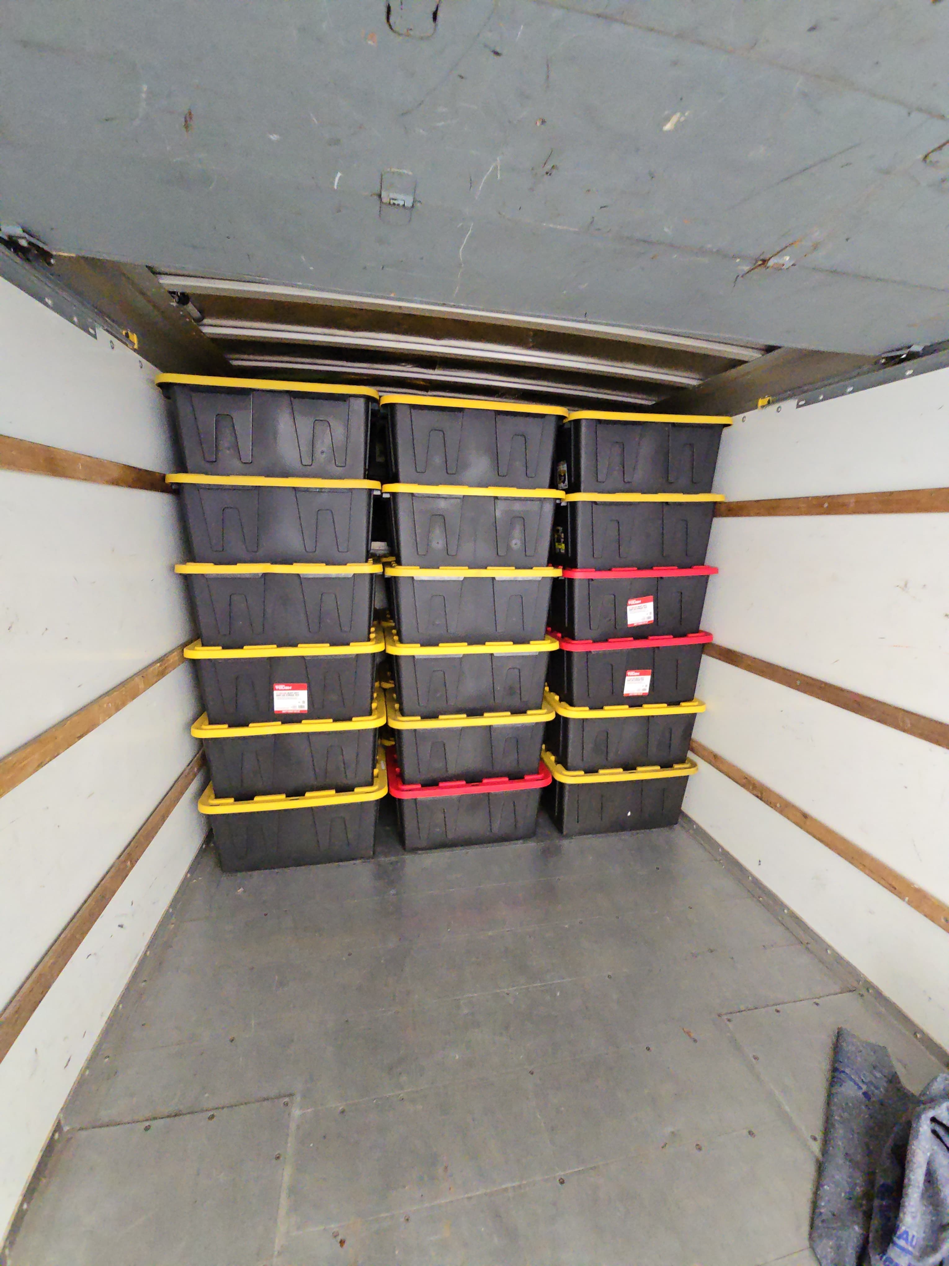 Columns of labeled totes stacked to the ceiling inside a moving truck
