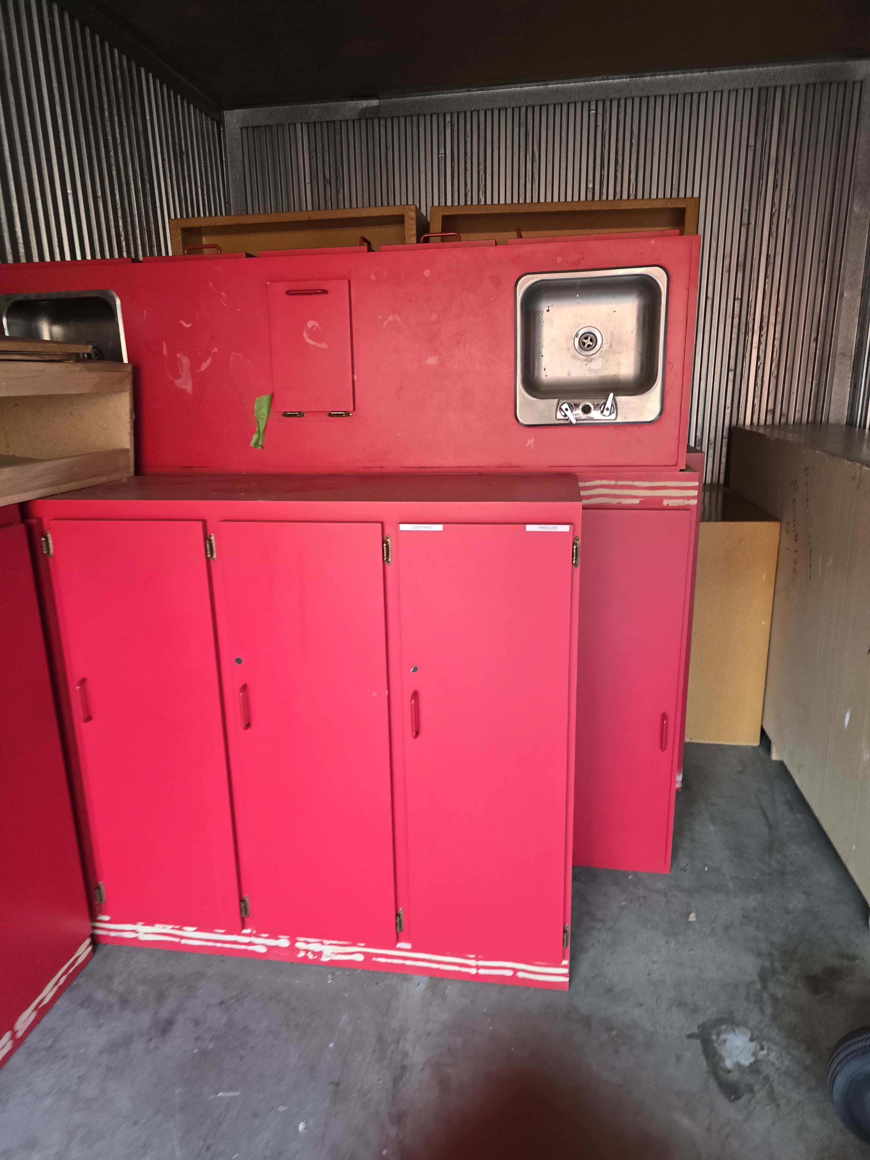 Red commercial cabinets and a stainless sink loaded in a box truck