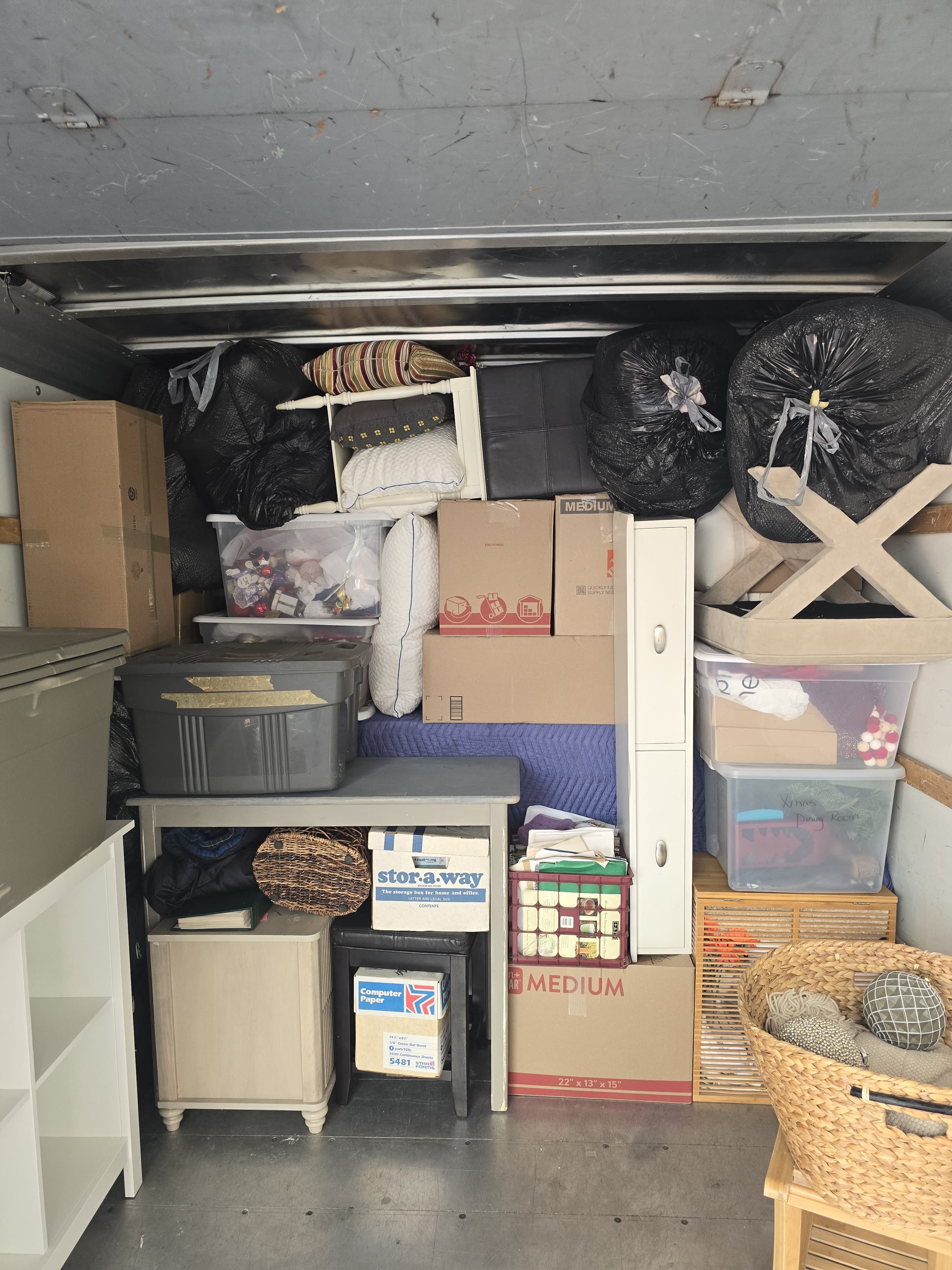 A moving truck packed floor to ceiling with boxes, bins and small furniture