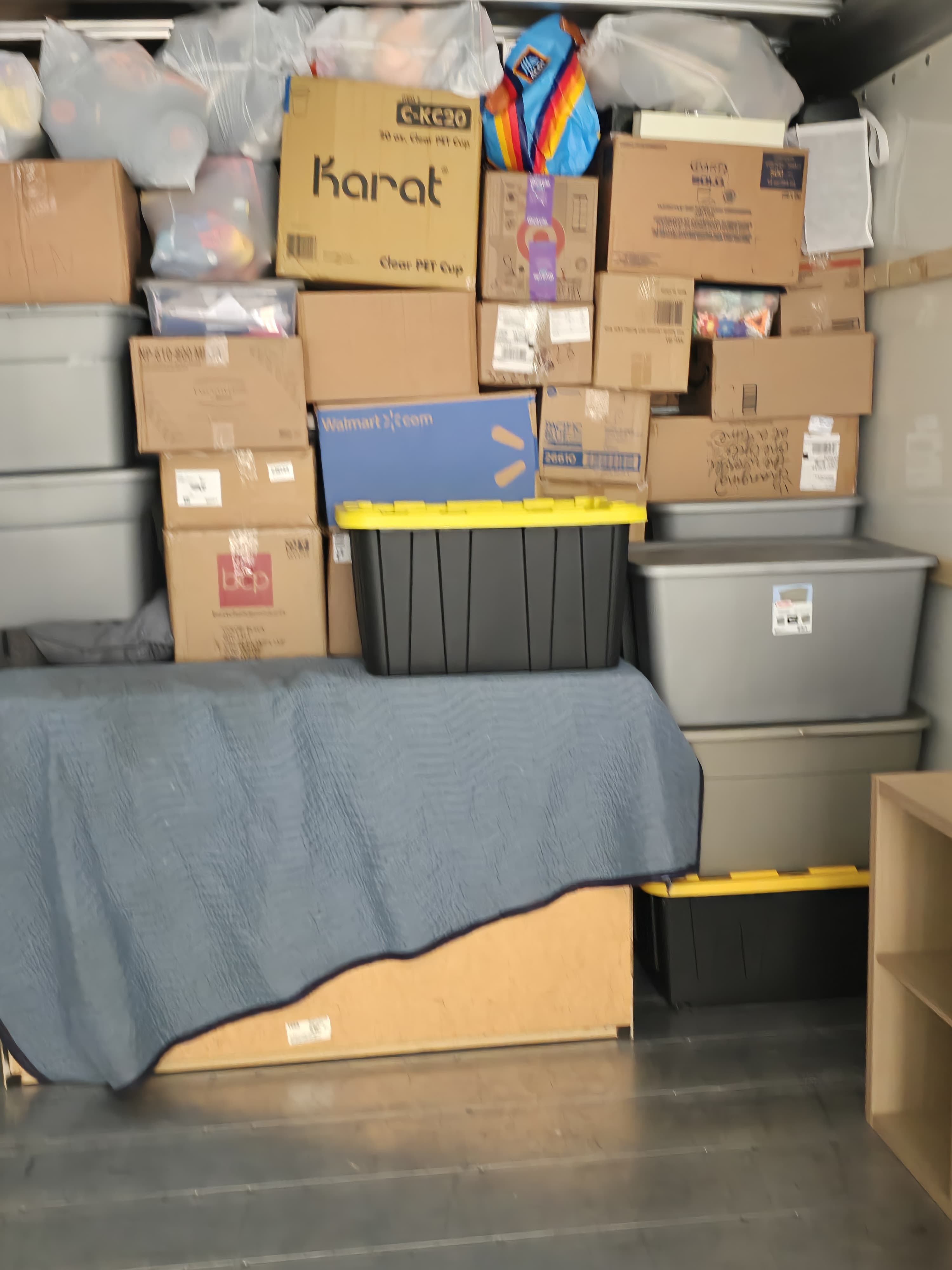 Labeled cartons and totes stacked on a pad-wrapped piece in a truck