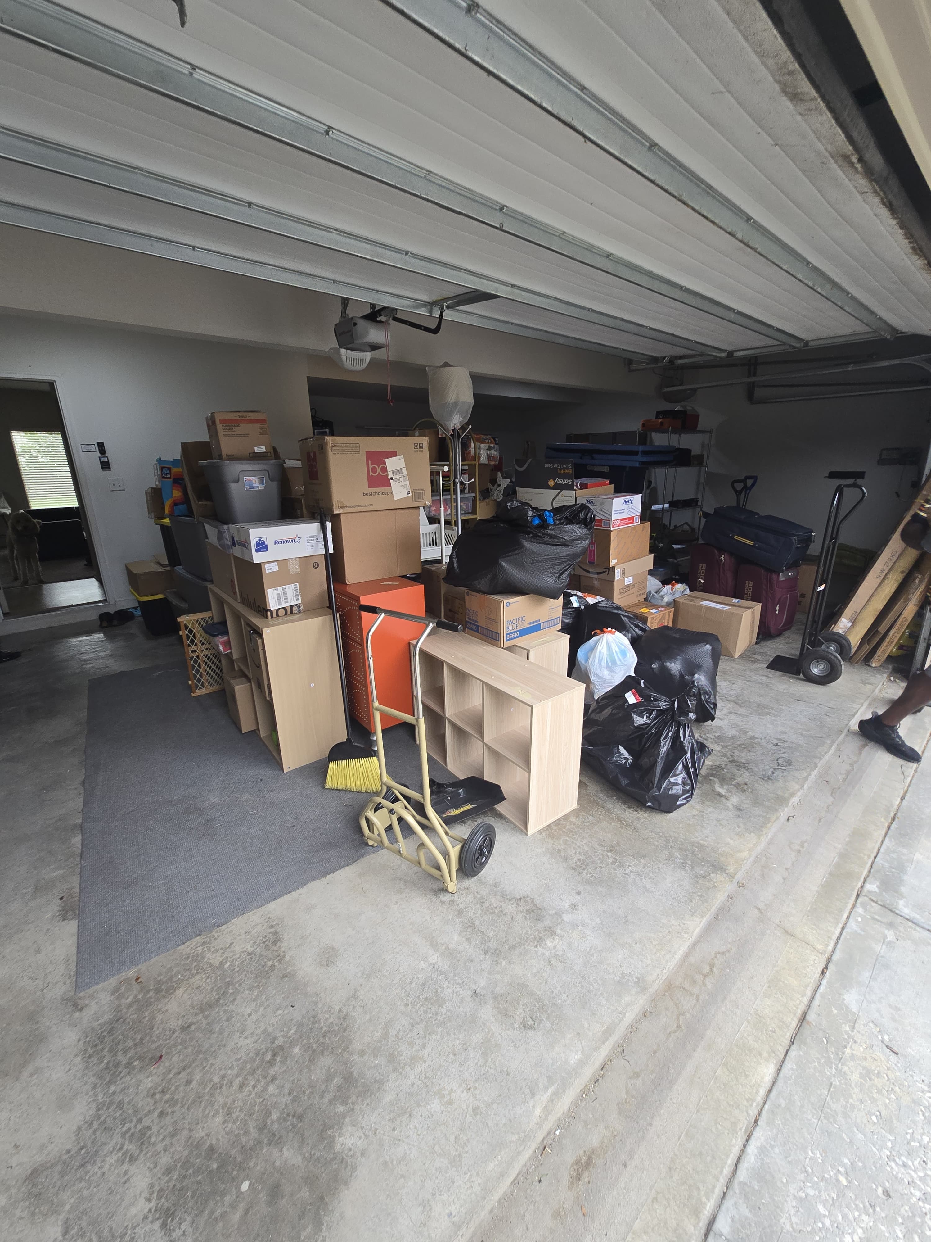 A garage staged for a move: boxes, totes, a cube shelf and a hand truck